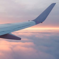 Flugzeugflügel beim Flug im Sonnenaufgang